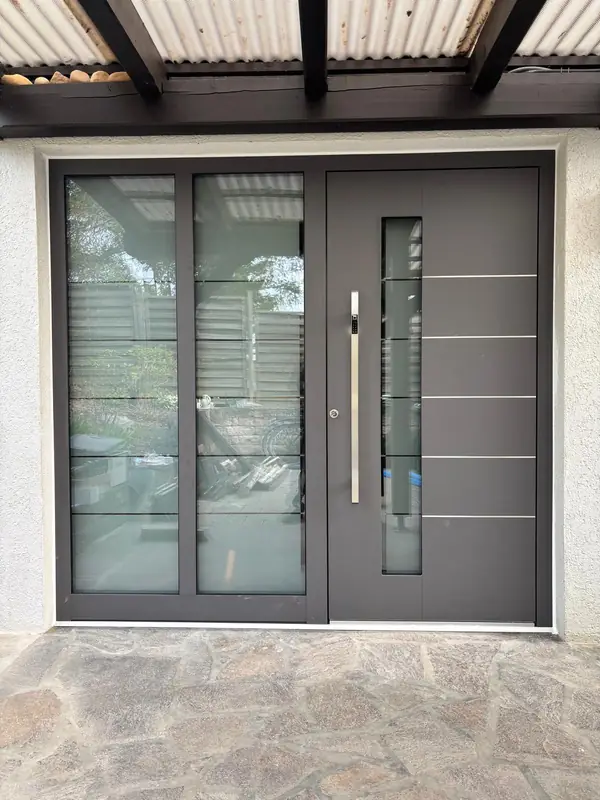 Anthrazitfarbene Haustür mit Glas-Seitenteil unter einem Vordach
