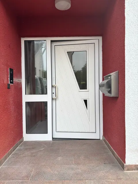 Vorher: weiße Haustür mit Seitenteil in roter Eingangsnische